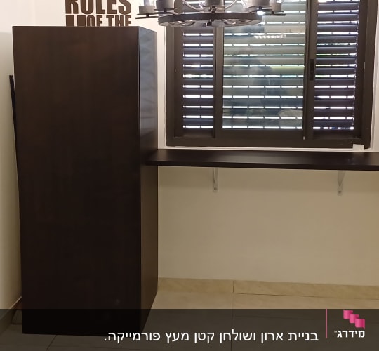 מדף עץ כהה מותקן על קיר עם סוגרים